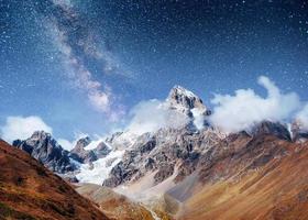 Fantastic starry sky. Autumn landscape and snow-capped peaks. Ma photo
