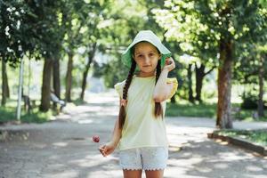 Funny child with candy lollipop, happy little girl eating big photo