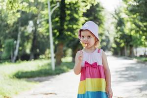 Funny child with candy lollipop, happy little girl eating big photo
