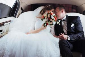 young couple in a car in wedding day photo