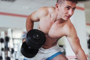 Portrait of a beautiful athletic guy muscles with weights photo