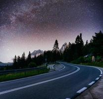 cielo estrellado sobre las montañas. la carretera asfaltada foto