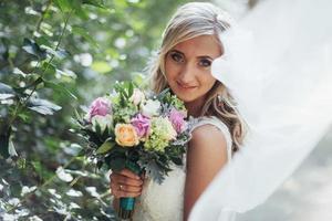 Portrait of a happy bride posing with veil photo
