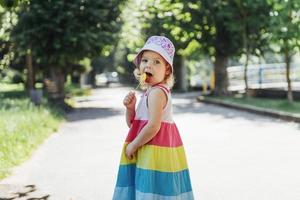 Funny child with candy lollipop, happy little girl eating big photo