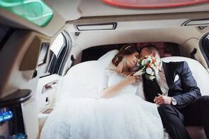 young couple in a car in wedding day photo