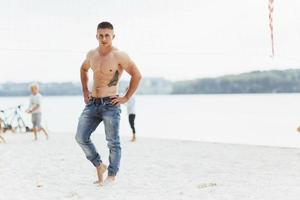 muscular male model with perfect body posing in blue jeans photo