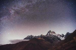 Fantastic starry sky. Autumn landscape and snow-capped peaks photo