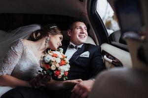 young couple in a car in wedding day photo