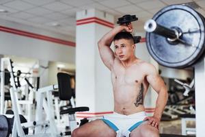 Portrait of a beautiful athletic guy muscles with weights photo