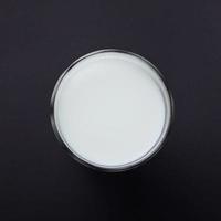vaso transparente de leche en un negro foto