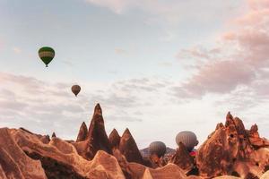 Globo aerostático sobrevolando el paisaje rocoso en Capadocia, Turquía. foto