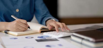 Close up woman using calculator working at office with reports document financial. photo