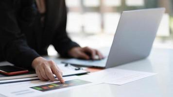 Close up Businesswoman hand holding pen and pointing at financial paperwork. photo