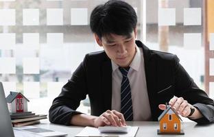 Real estate agent with model of house use calculator for sale,real estate agent home loan working at the office.