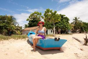 señora sentada en un viejo barco de pesca de madera divirtiéndose en la playa en corumbau, bahia, brasil foto
