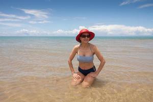 dama en la playa sentada en un banco de arena durante la marea baja en ponta do corumbau, brasil foto