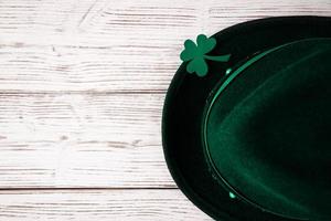 feliz st. día de San Patricio. sombrero de duende y trébol de trébol sobre un fondo de madera clara. foto