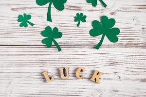 Word luck and shamrock clover leaves on a white wooden background. Happy St. Patrick's Day. photo