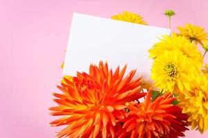 tarjeta de felicitación en blanco en ramo de flores de verano amarillas y rojas sobre fondo rosa. foto