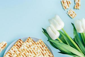 Happy Passover concept. Matzo and white tulips on a blue background. Religious Jewish holiday Pesach. photo