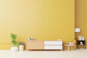 mueble para tv o colocar objetos en un salón moderno con lámpara, mesa, flor y planta sobre fondo de pared amarillo.