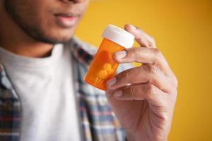 young man hand holding medicine pill container photo