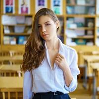 young woman sitting at table in white shirt and signing papers, business concept photo