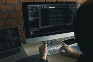 Hacker in the hood working with computer and holding credit card with payment hacking concept. photo