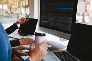 trabajando en la mañana con hombres de negocios están tomando café que trabaja con desarrolladores de software para analizar juntos el código escrito en el programa en la computadora. foto