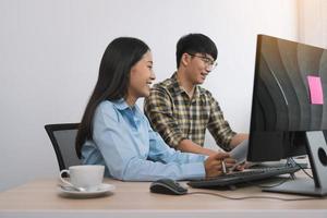 jóvenes programadores asiáticos que trabajan en equipo mientras crean nuevos códigos de computadora en una computadora de escritorio en la oficina.