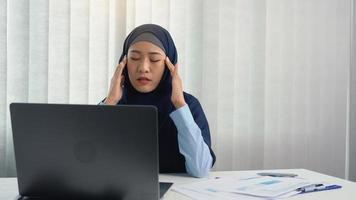 Muslim woman kneaded her head with a hand massage while suffering from a migraine headache. photo