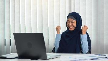 Muslim woman is doing a happy expression in completing her goals. photo