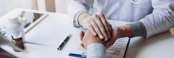 Doctor is holding the patient's hand and giving hope about treating the symptoms of the disease. photo