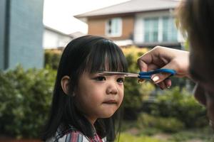 Mom was cutting her hair for her daughter at home. photo