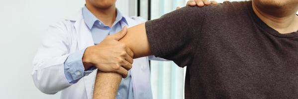 los fisioterapeutas presionan el hombro del paciente para comprobar si hay dolor. foto
