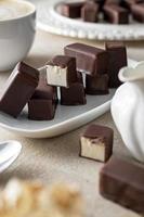 caramelos de chocolate con relleno de malvavisco sobre fondo brillante servido con una taza de café