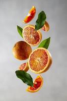Bloody orange levitation. Oranges slices in the aer with green leaves. Abstract citrus fruit composition. photo