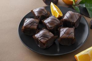 Chocolate candy cakes with orange filling on brown background. Chocolate dessert.