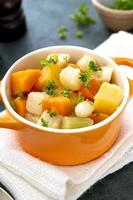 cierre las verduras de raíz horneadas en un tazón de naranja. comida vegana. foto
