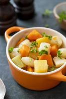 cierre las verduras de raíz horneadas en un tazón de naranja. comida vegana. foto