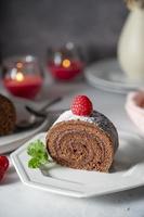 Chocolate roll cake or swiss dessert cake with raspberries. Romantic mood with candles.