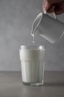 Milk poured into glass. Dairy product concept. photo