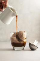 café affogato, espresso caliente vertido sobre helado de chocolate en vidrio sobre fondo brillante foto