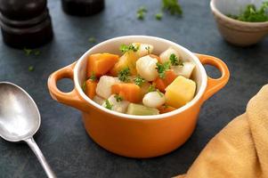 verduras de raíz asadas o al horno con hierbas frescas, verduras de naranja en el plato. comida vegana. foto