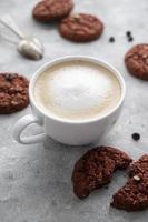 café y galletas. avena, galletas saludables y taza de café con espuma de leche, concepto de desayuno. foto