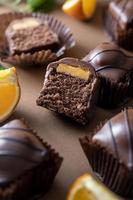 Chocolate slicd candy cakes with orange filling on brown background. photo