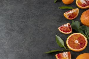 Bloody oranges slices with fresh leaves. Abstract citrus fruit background with copy space.