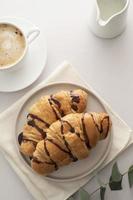 croissants con taza de chocolate y café sobre fondo brillante. hora del desayuno