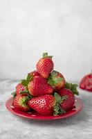 Strawberry fresh fruits in a plate, grey background. Healthy food concept