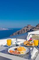 Breakfast time in Santorini in hotel. Luxury mood with fresh omelet and fruits with juice over sea view. Luxurious summer traveling holiday background. Happy relax vibes, couple morning closeup table photo